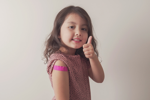 Young girl receives her COVID-19 vaccine and gives thumbs up.